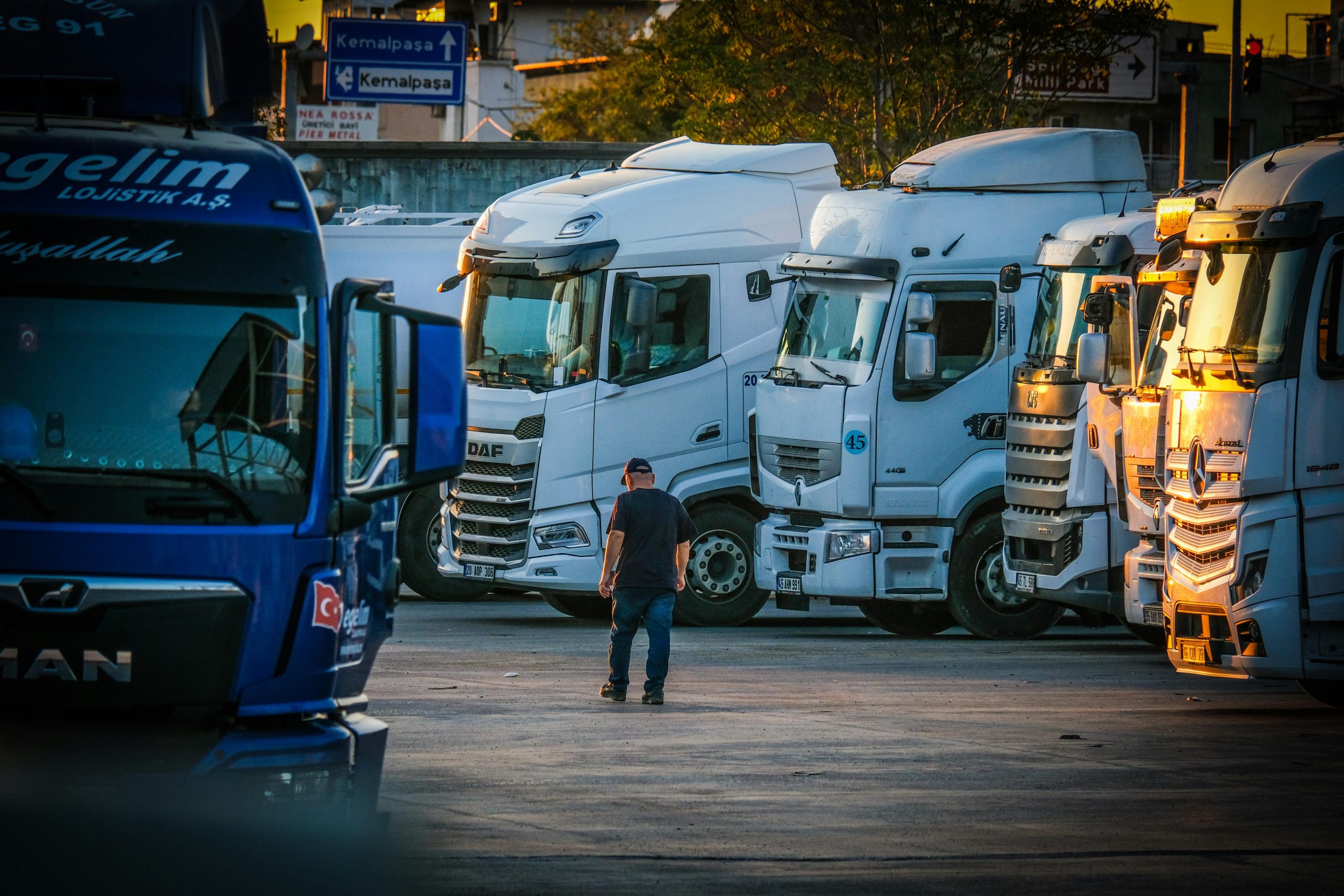 Frota de veículos pesados parada em centro de distribuição ao final do dia, representando a logística e o tempo de vida útil dos ativos.